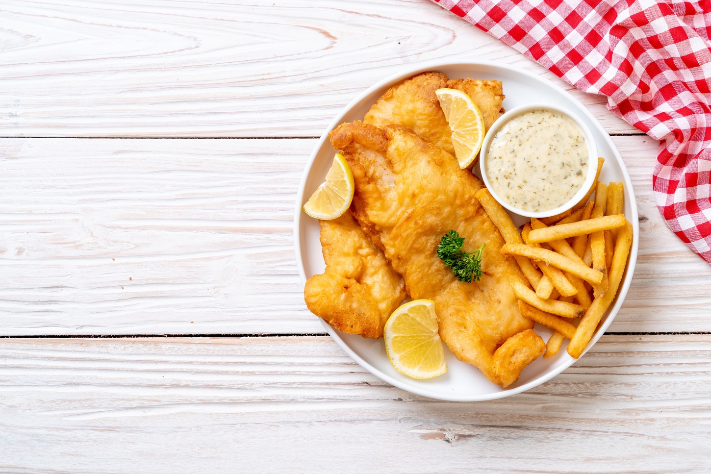 plate of fish and chips on white wood table