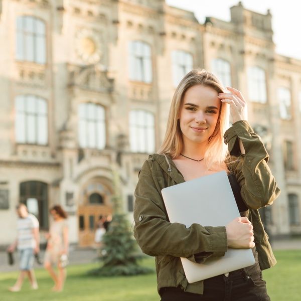 student outside accommodation holding laptop