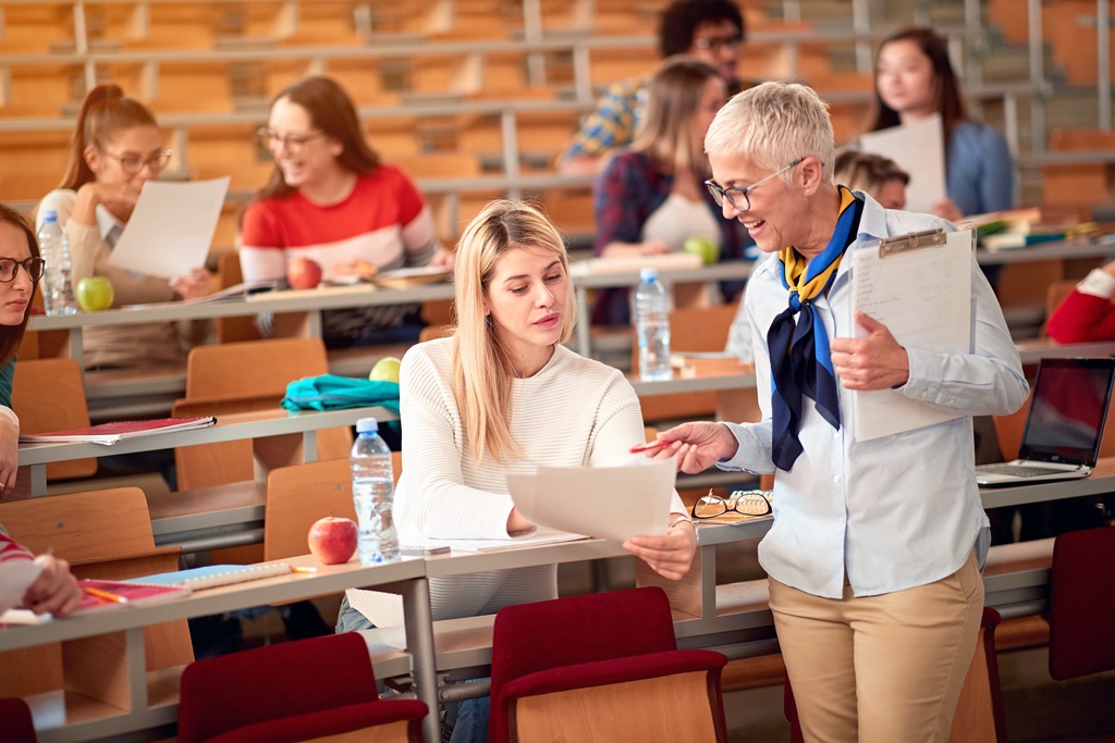 lecturer speaking to student in lecture hall