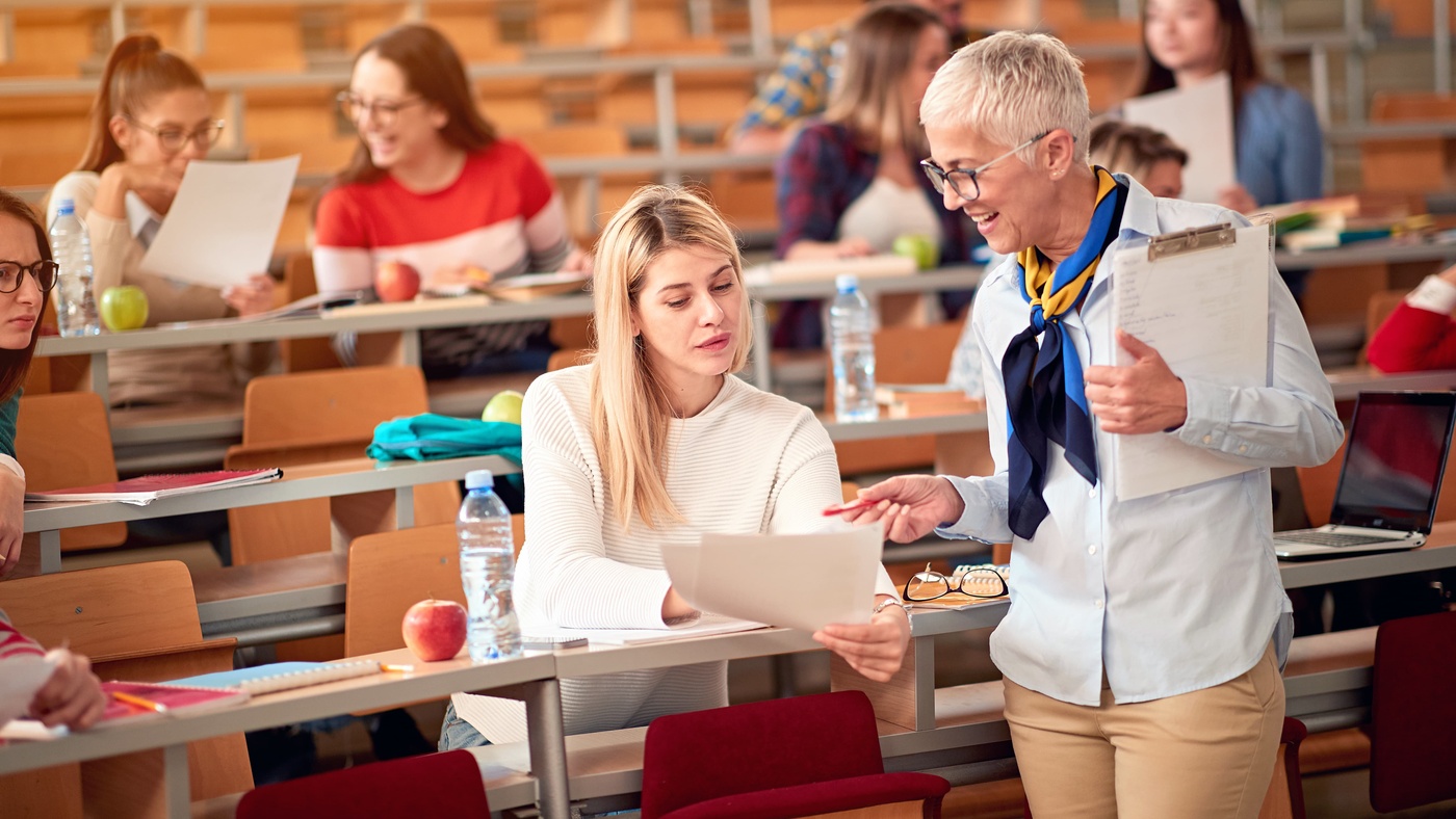 lecturer speaking to student in lecture hall