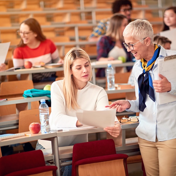 lecturer speaking to student in lecture hall