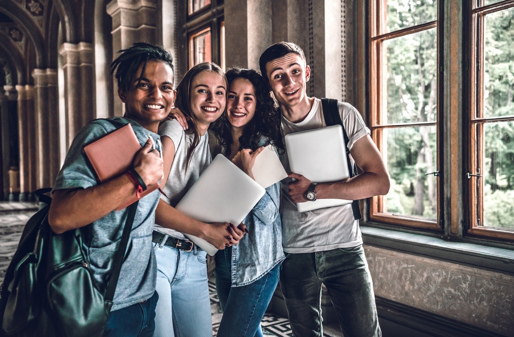 students in hallway posing for photo with laptops