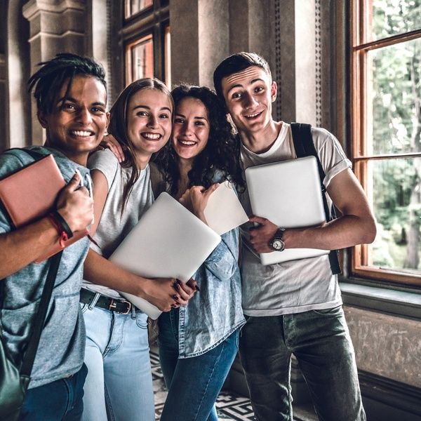 students in hallway posing for photo with laptops