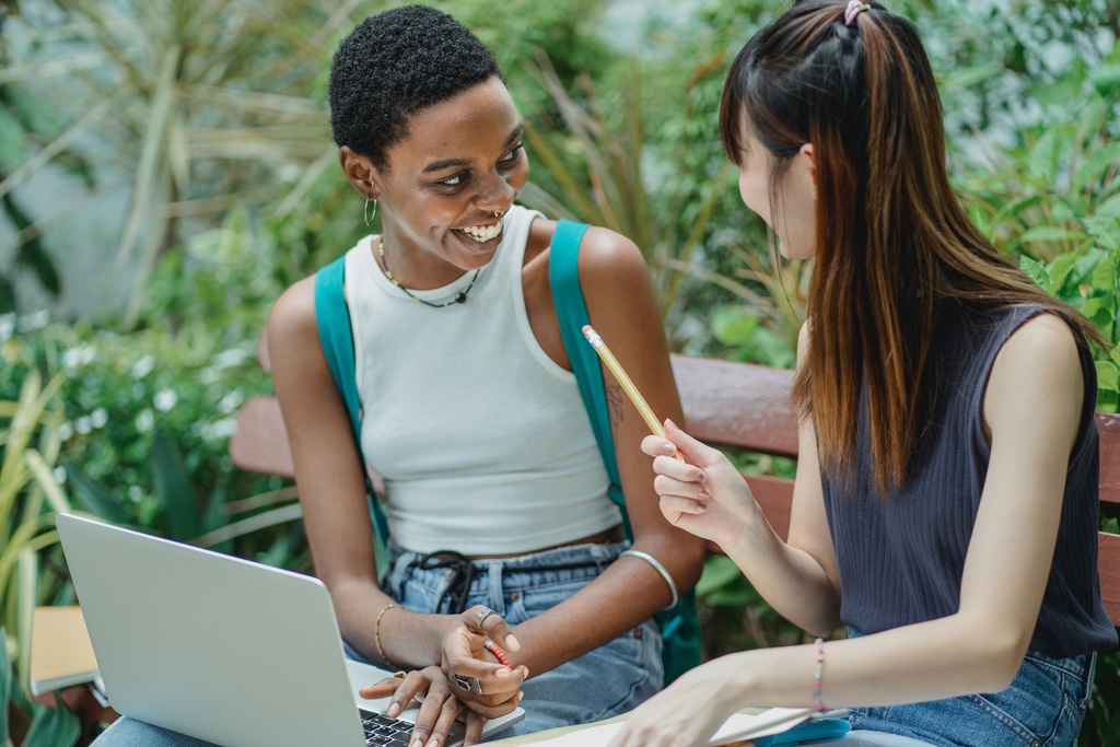 Students sitting and talking in front of a laptop