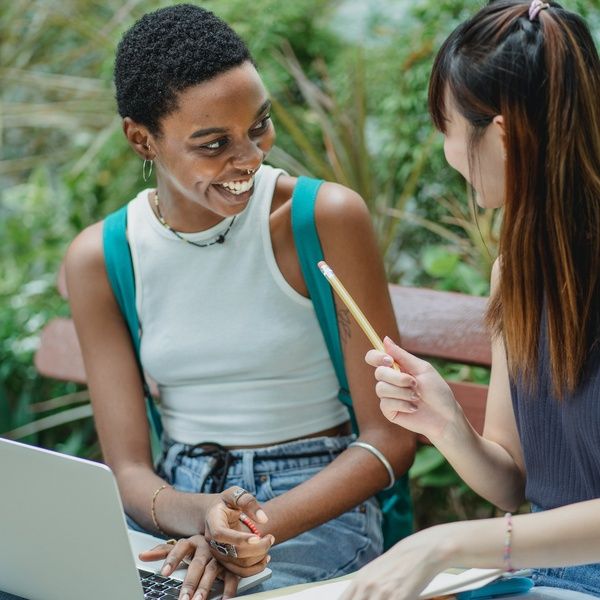 Students sitting and talking in front of a laptop