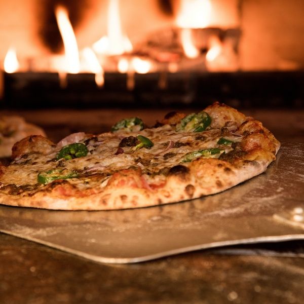 pizzas in front of stone oven