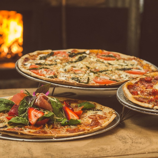 three pizzas next to stone oven