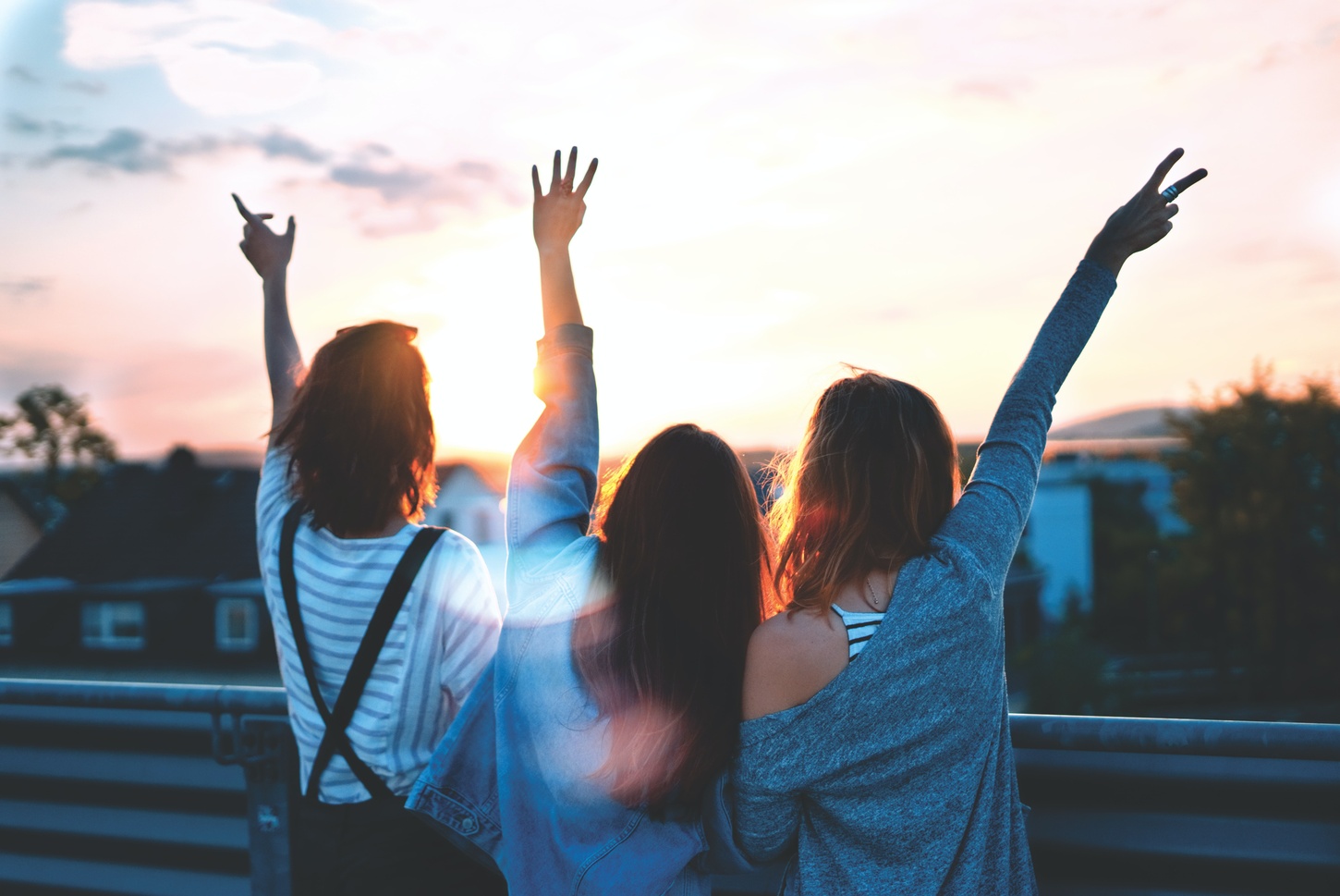 three girls raising hands outside