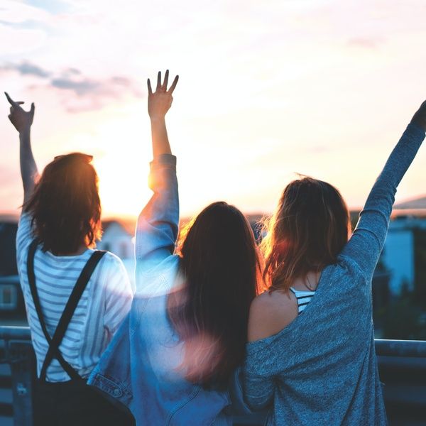 three girls raising hands outside