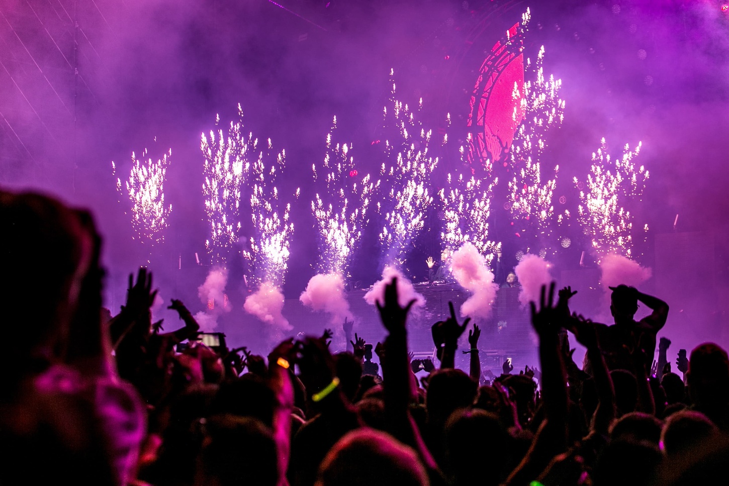 Dj playing music and young people dancing in a night club