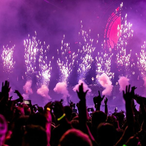 Dj playing music and young people dancing in a night club